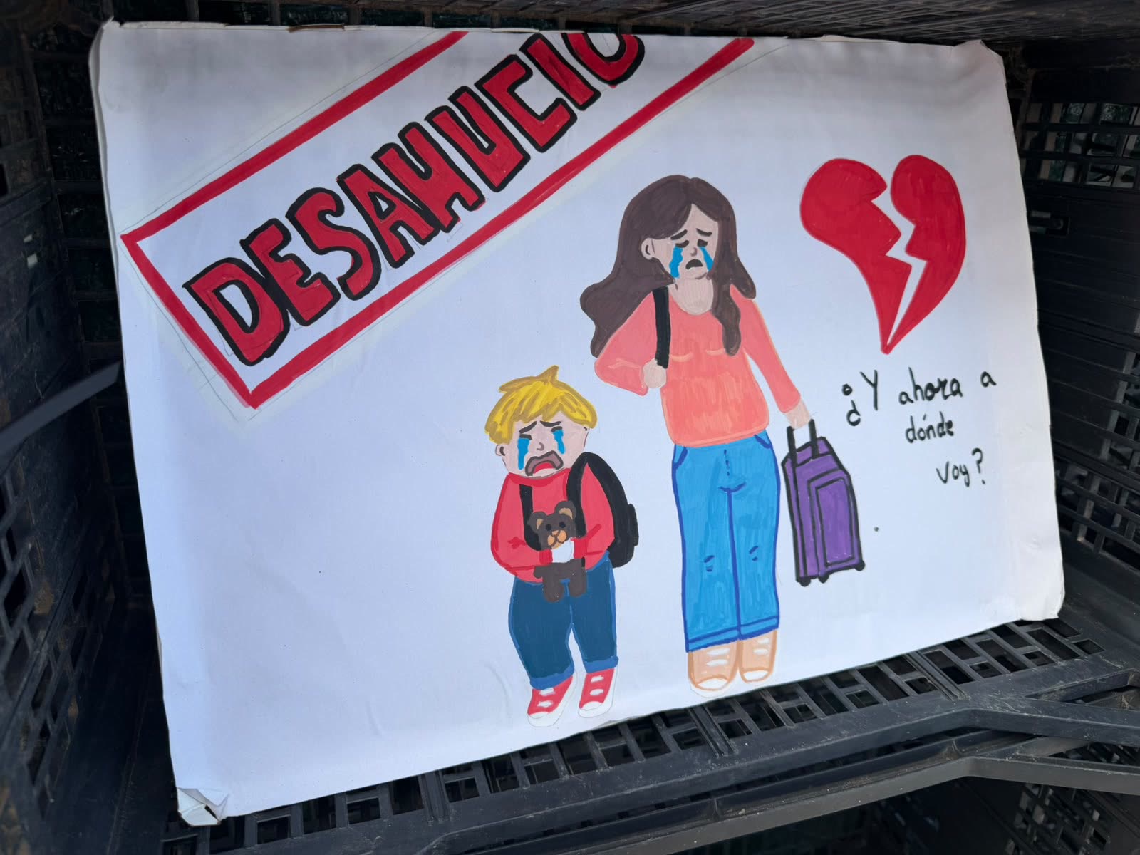 Cartel pintado a mano con la palabra «Desahucio» y una familia con las maletas